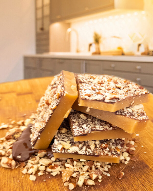 Candy by Grant - Our Dark Chocolate Pecan Toffee with a side view, showing its thickness and the layer of chocolate and pecans.