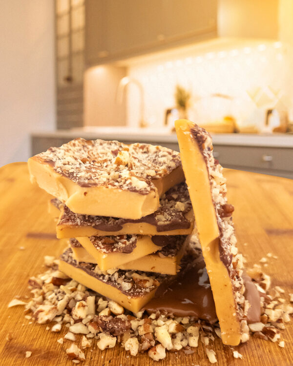 Candy by Grant - Our Milk Chocolate Pecan Toffee with a side view, showing its thickness and the layer of chocolate and pecans.
