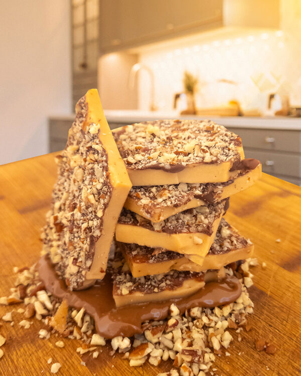 Candy by Grant - Our Milk Chocolate Pecan Toffee with a side view, showing its thickness and the layer of chocolate and pecans.